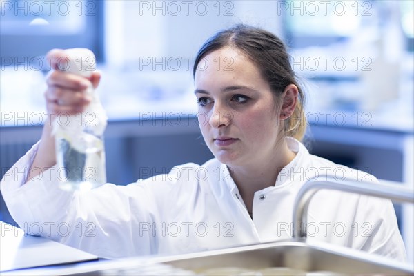 Young lab technician with lab glove and sample working in a lab with lab equipment