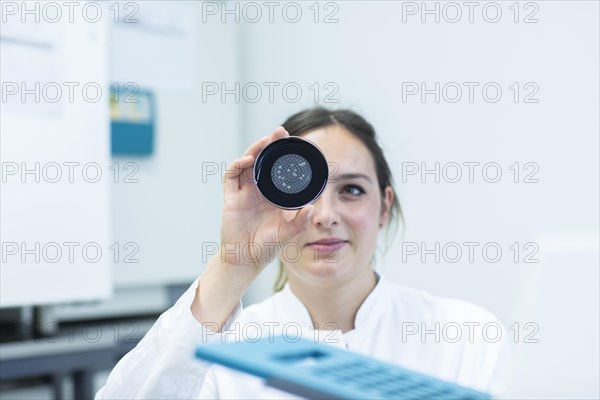 Lab technician with sample in petri dish working in a lab with lab equipment