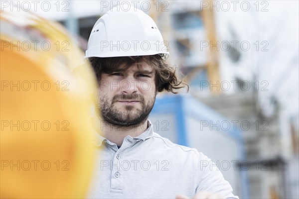 Technician with beard middle aged and wearing polo shirt and helmet outside at work