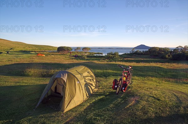 Tunnel tent and touring bike on spacious meadow