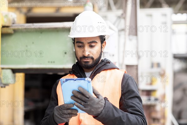 Technician with beard and helmet works in a workshop