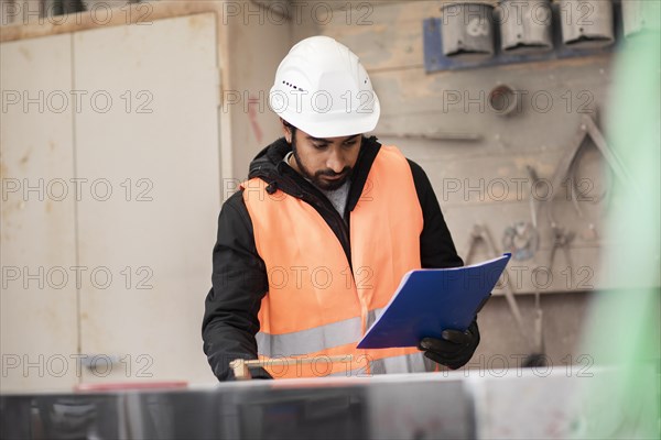 Technician with beard and helmet works in a workshop