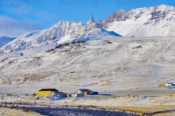 River and farm in front of snow-capped mountains