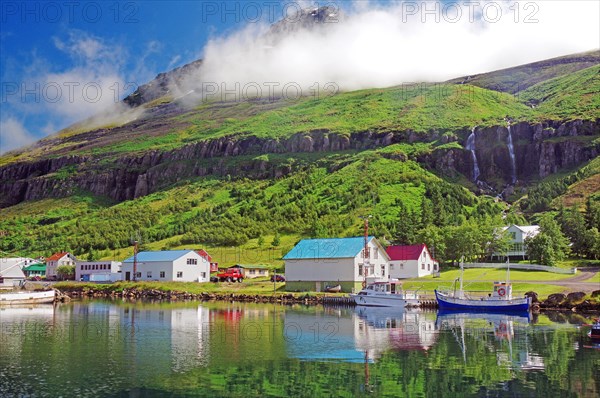 Boats and small houses reflected in the fjord