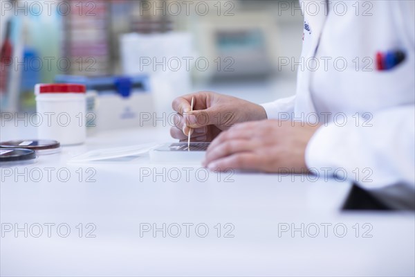 Hand of a lab technician with wooden stick and sample working in a laboratory with laboratory equipment
