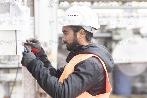 Technician with beard and helmet works in a workshop