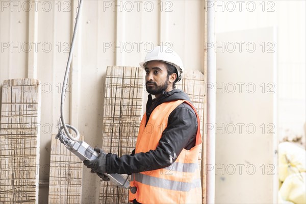 Technician with beard and helmet works in a workshop