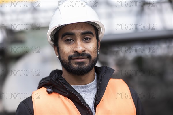 Technician with beard and helmet works in a workshop