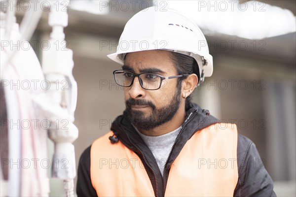 Technician with beard and helmet works in a workshop