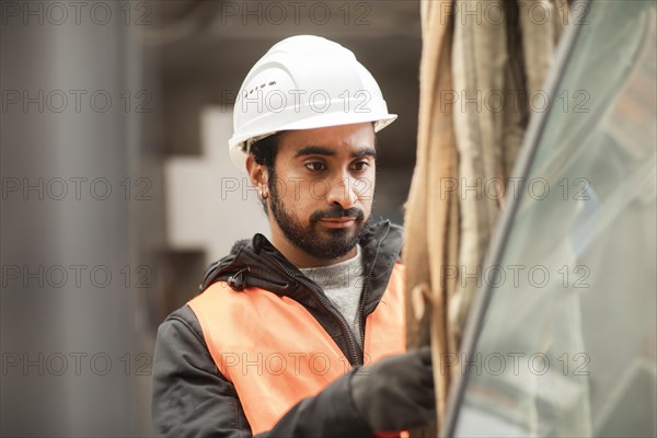 Technician with beard and helmet works in a workshop