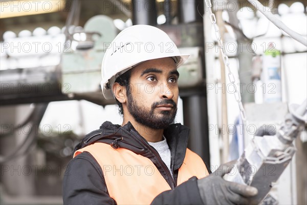Technician with beard and helmet works in a workshop