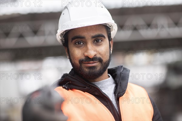 Technician with beard and helmet works in a workshop