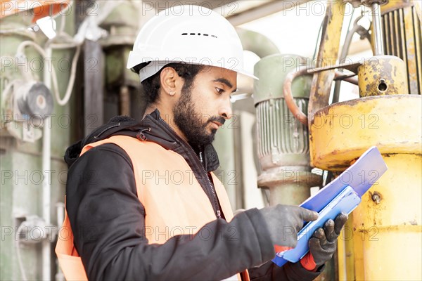 Technician with beard and helmet works in a workshop