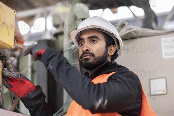 Technician with beard and helmet works in a workshop