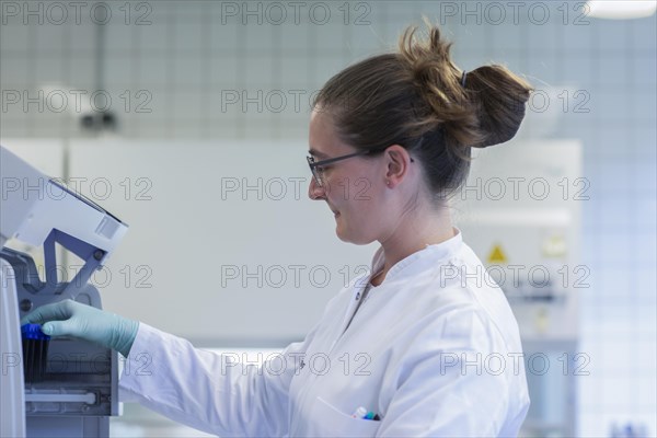 Young lab technician with lab glove and sample working in a lab with lab equipment