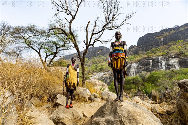 Traditional dressed young girls from the Laarim tribe standing on a rock