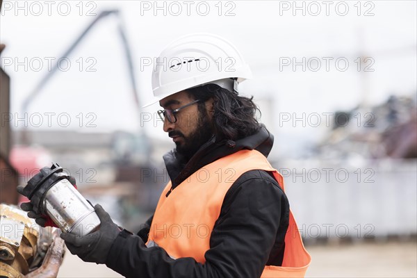 Technician with beard and helmet working in a recycling yard