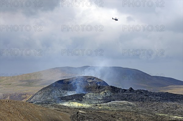 Helicopter over smoking volcanic crater Fagradalsfjall