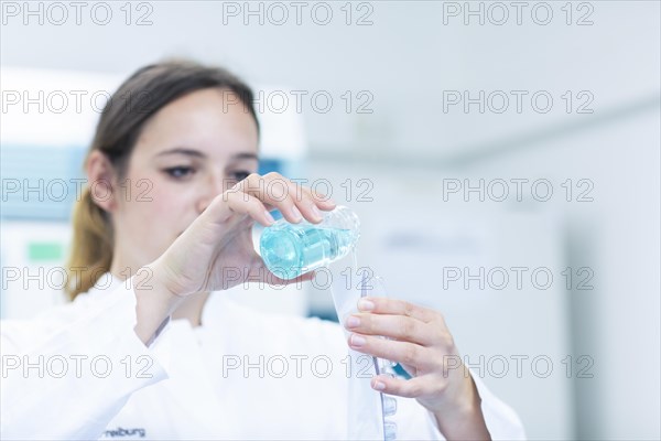 Young laboratory assistant with sample and laboratory glasses working in a laboratory with laboratory equipment