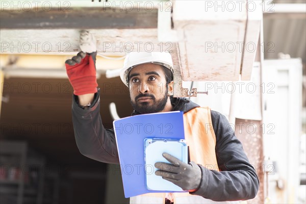 Technician with beard and helmet works in a workshop