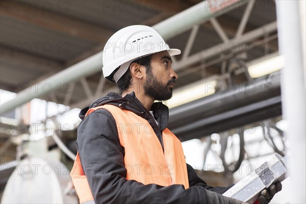 Technician with beard and helmet works in a workshop