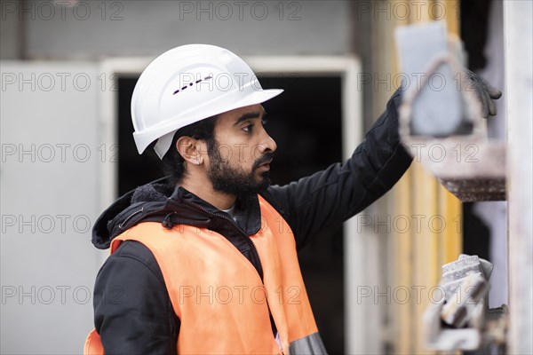 Technician with beard and helmet works in a workshop