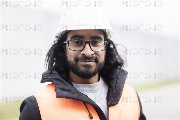 Technician with beard and helmet works in a workshop