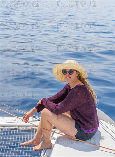 Young woman with hat sitting on deck