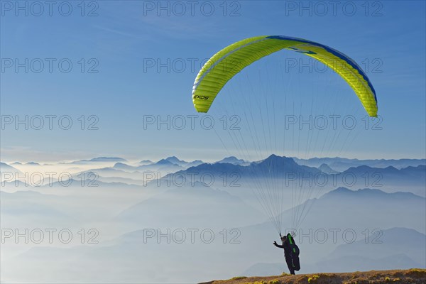 Paraglider taking off with the peaks of the Lake Garda mountains and Bergamo Alps