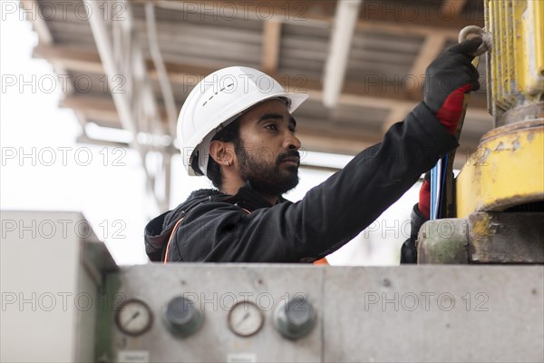 Technician with beard and helmet works in a workshop