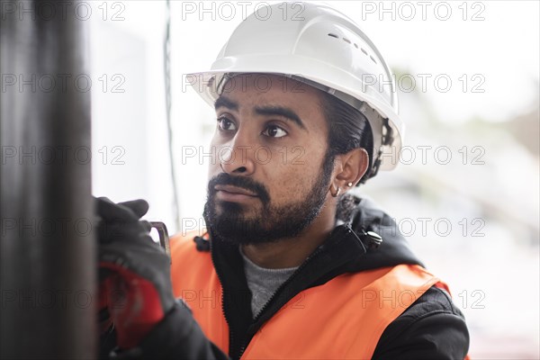 Technician with beard and helmet works in a workshop