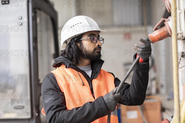 Technician with beard and helmet works in a workshop