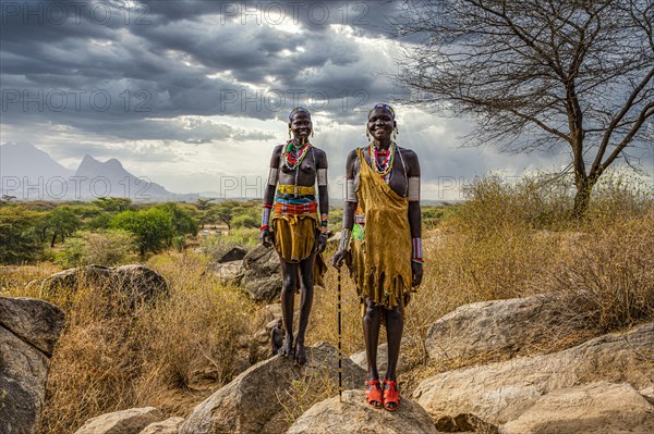 Traditional dressed young girls from the Laarim tribe standing on a rock