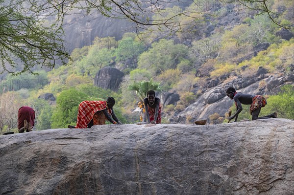 Young girls grinding Sorghum on a rock