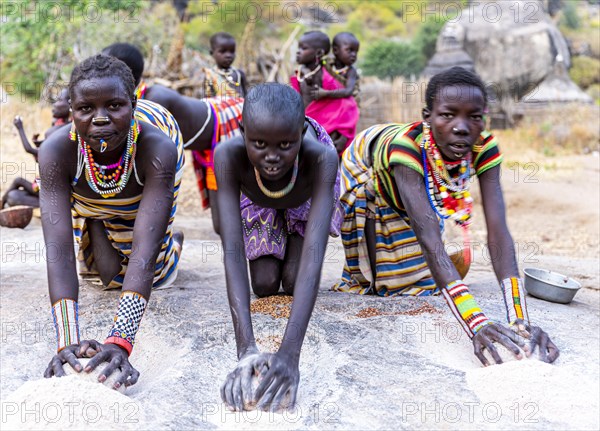 Young girls grinding Sorghum on a rock