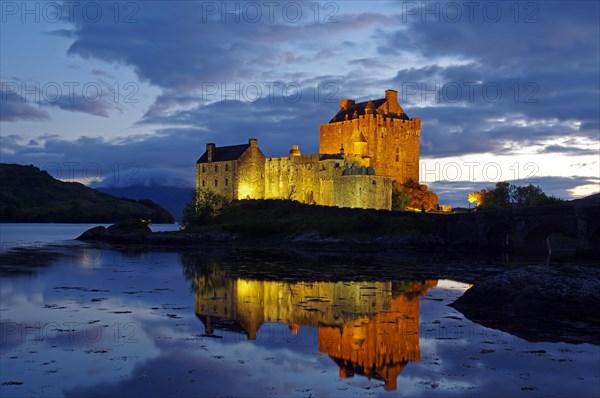 Castle with bridge is lit differently at dusk