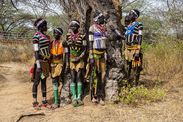 Traditional dressed young girls from the Laarim tribe chatting under a tree