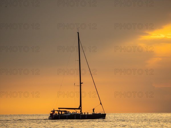 Sailing ship with gathered sails in front of dark clouds