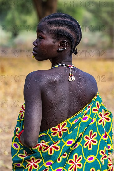 Traditional dressed young girls from the Laarim tribe with body scars on her back