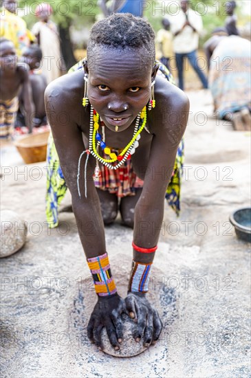 Young girls grinding Sorghum on a rock