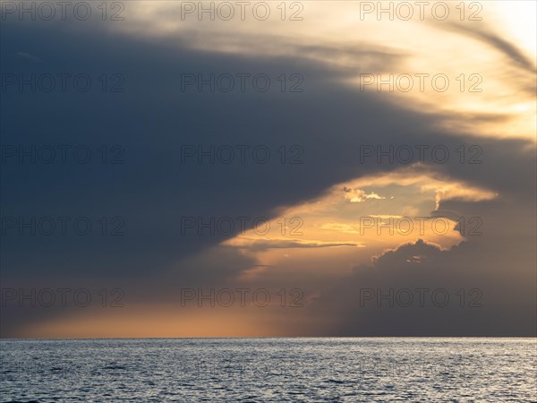 Dark clouds over the sea in front of the setting sun