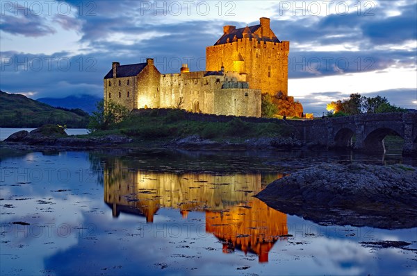 Castle with bridge is lit differently at dusk