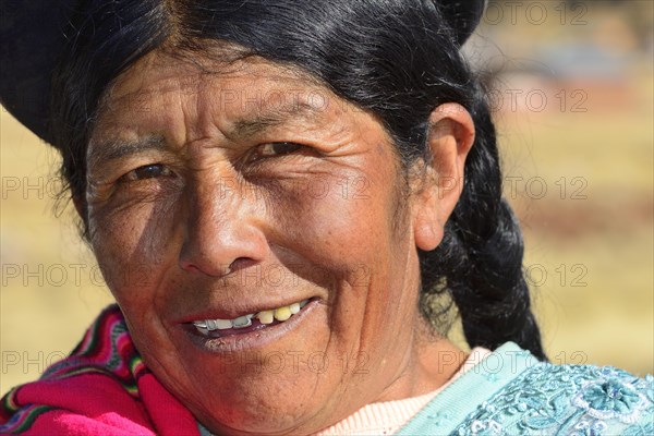 Older indigenous woman with hat smiling at the camera