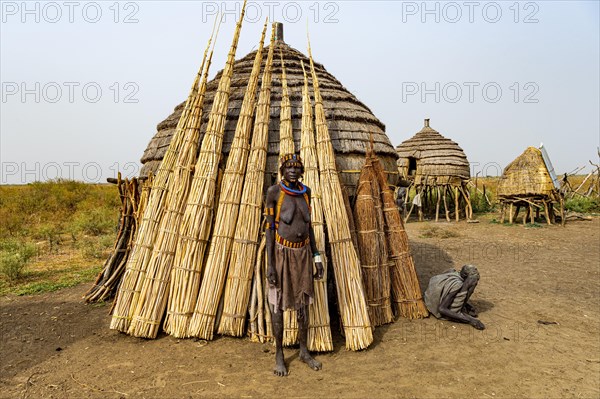 Woman before her hut with ready prepared reeds