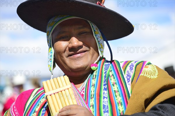 Indigenous man in traditional costume with pan flute during a parade