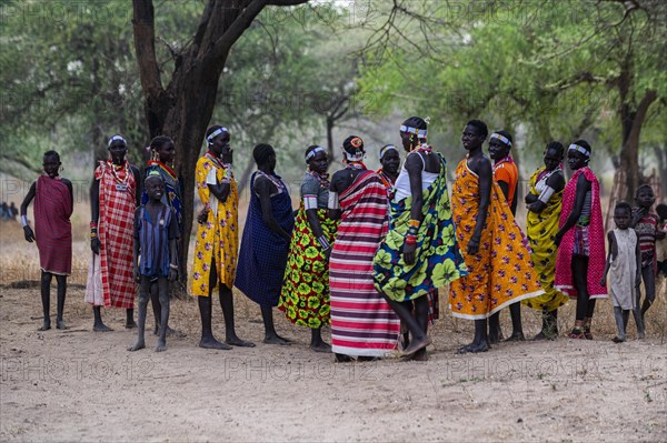 Traditional dressed young girls from the Laarim tribe chatting under a tree