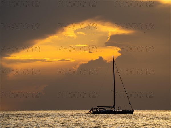 Sailing ship with gathered sails in front of dark clouds
