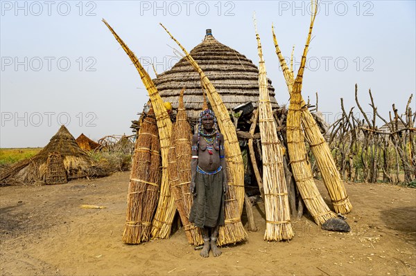 Woman before her hut with ready prepared reeds