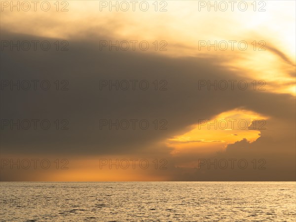 Dark clouds over the sea in front of the setting sun