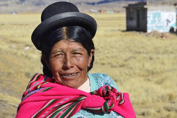 Older indigenous woman with hat smiling at the camera